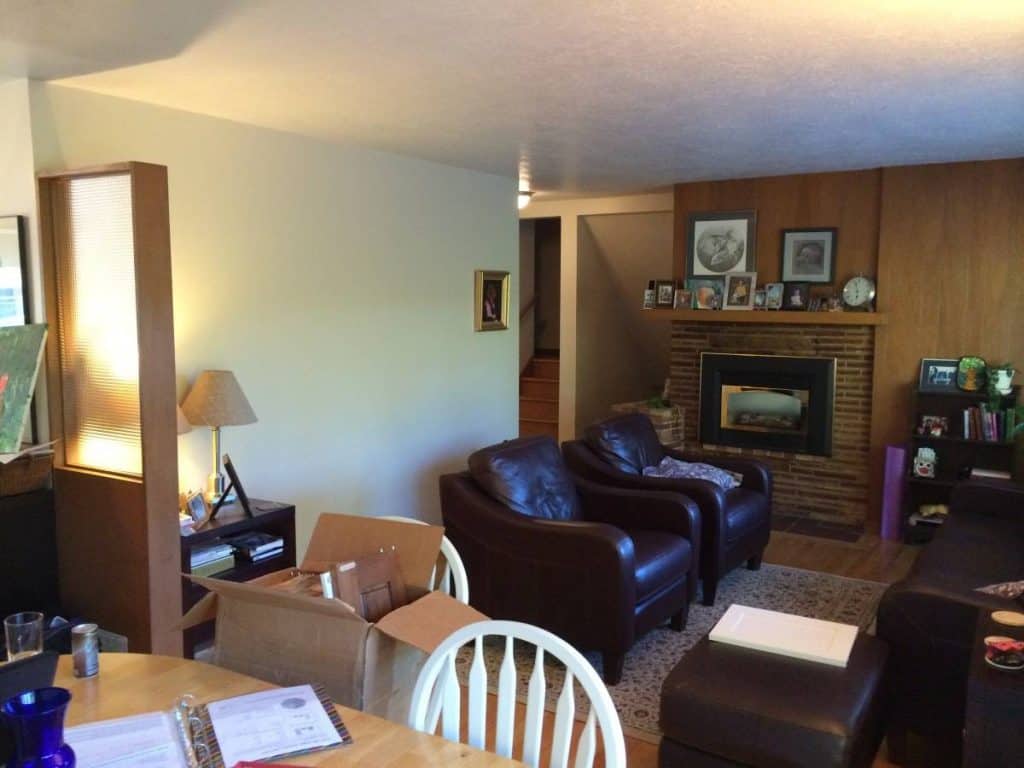 Notice the load bearing wall dividing the living room from the kitchen, the old brick fireplace, and the wood paneling….
