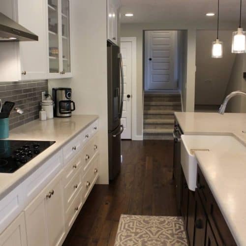 project_full-house-remodel_11 Crisp… clean… and open. Customer now has a 14 foot long center island for all of their entertaining needs! We sprayed all of the new cabinets in place with a white precatalized lacquer, and installed a knotty walnut center island with a farm style sink.