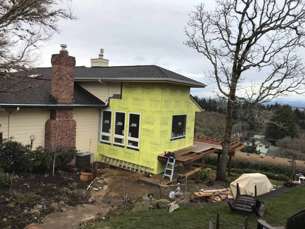 Additional windows are installed, and the house is wrapped.