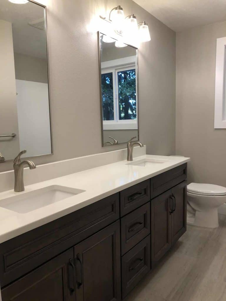 Two separate washing stations makes this bathroom more functional for a growing family. We incorporated rectangular undermount sinks for a more modern feel and installed a beautiful luxury sheet vinyl to update the floors. The simple quartz countertops with matching backsplash keeps this bathroom feeling simple and clean!