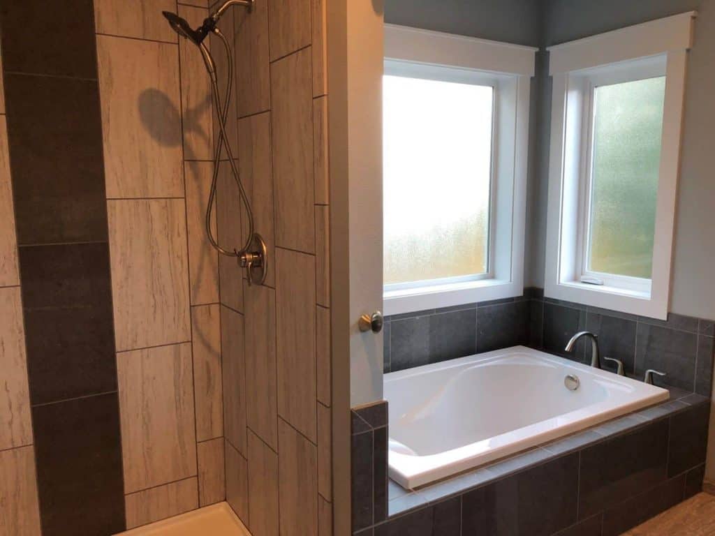 The shower is complete with 12x24 tile running vertical from floor to ceiling, and a “waterfall” accent that matches the tub surround.