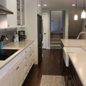 AFTER Crisp… clean… and open. Customer now has a 14 foot long center island for all of their entertaining needs! We sprayed all of the new cabinets in place with a white precatalized lacquer, and installed a knotty walnut center island with a farm style sink.