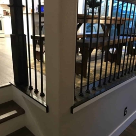 AFTER The new stair rail consisted of black square metal spindles and the newel post and solid wood railing were stained to match the new floors.