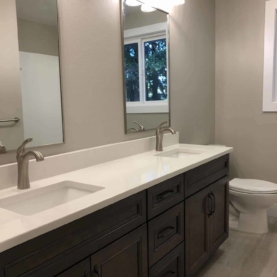 AFTER Two separate washing stations makes this bathroom more functional for a growing family. We incorporated rectangular undermount sinks for a more modern feel and installed a beautiful luxury sheet vinyl to update the floors. The simple quartz countertops with matching backsplash keeps this bathroom feeling simple and clean!