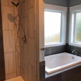 AFTER The shower is complete with 12x24 tile running vertical from floor to ceiling, and a “waterfall” accent that matches the tub surround.