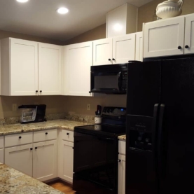 AFTER The homeowner wanted to keep the existing appliances but wanted to change all other elements. They especially wanted simple white cabinets and wood looking floors.